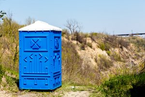 porta potty next to a trail outdoors